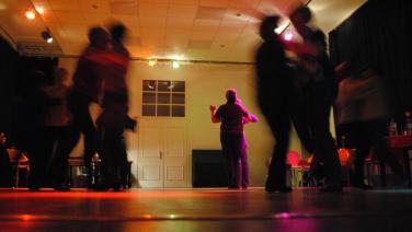 Mehrere Paare tanzen in großem Raum.